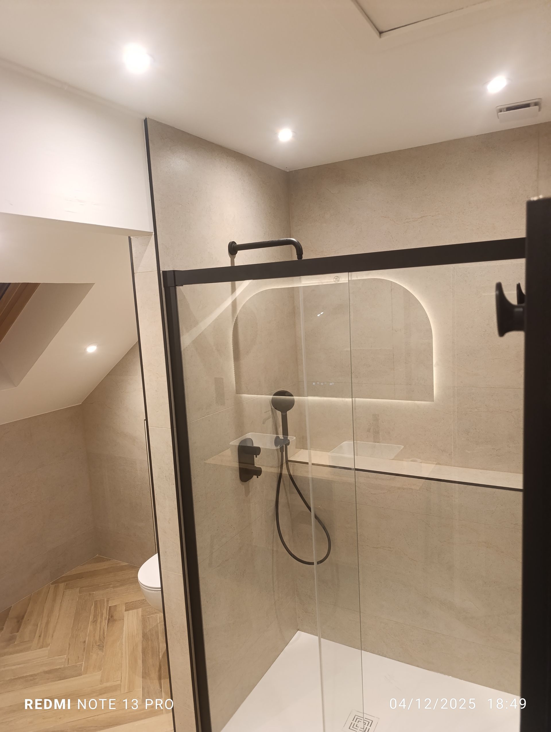 Salle de bains moderne avec cabine de douche en verre et carrelage aux tons neutres.