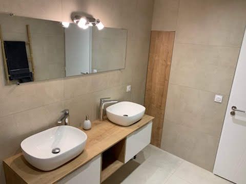 Salle de bains moderne avec toilettes, lavabo et grand miroir avec éclairage intégré.