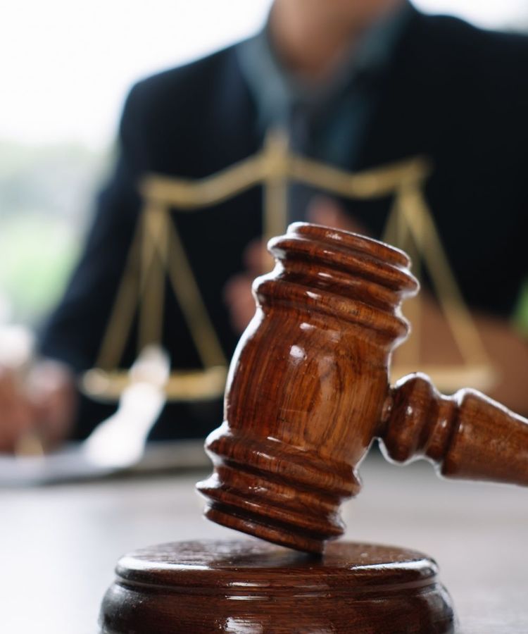El mazo de un juez se encuentra sobre una mesa frente a una balanza de justicia.