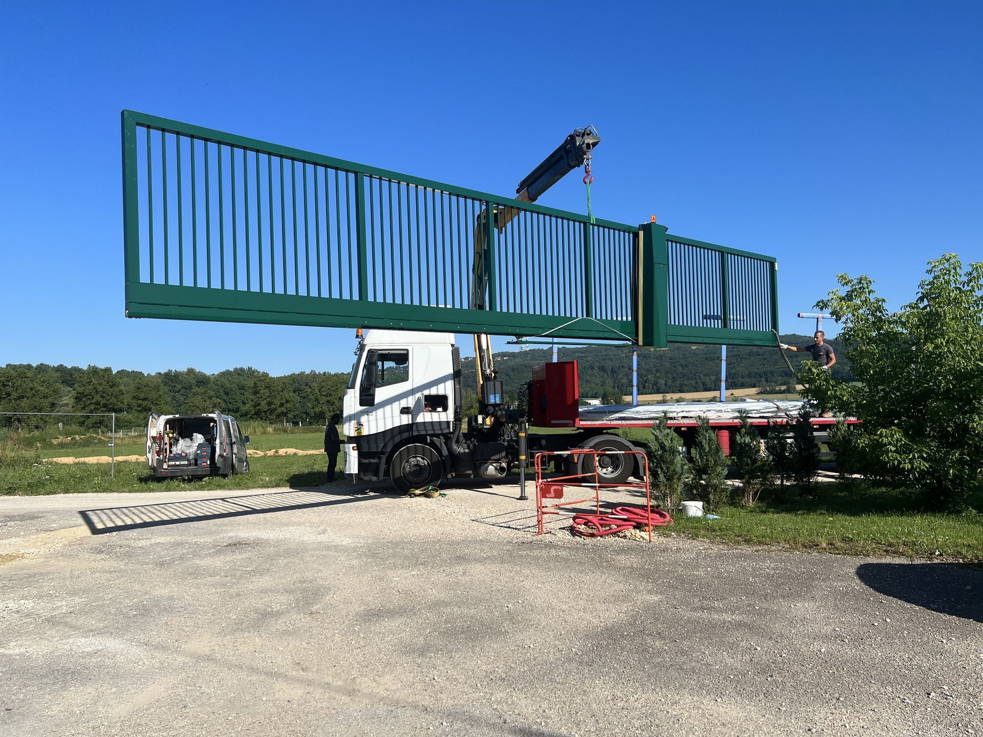Une grue sur un camion qui soulève un portail vert