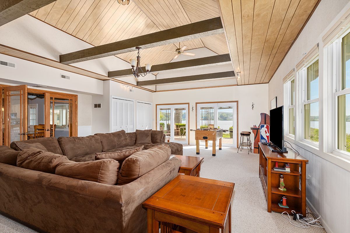 Spacious lodge living room with a brown sectional, wooden ceiling, and waterfront view.