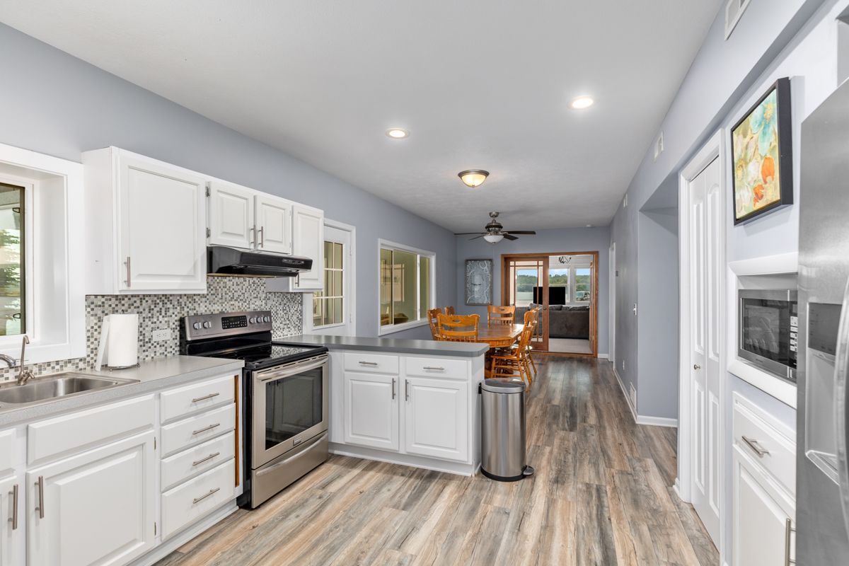 Kitchen in lodge with white cabinets, stainless steel appliances, and wood-look flooring.