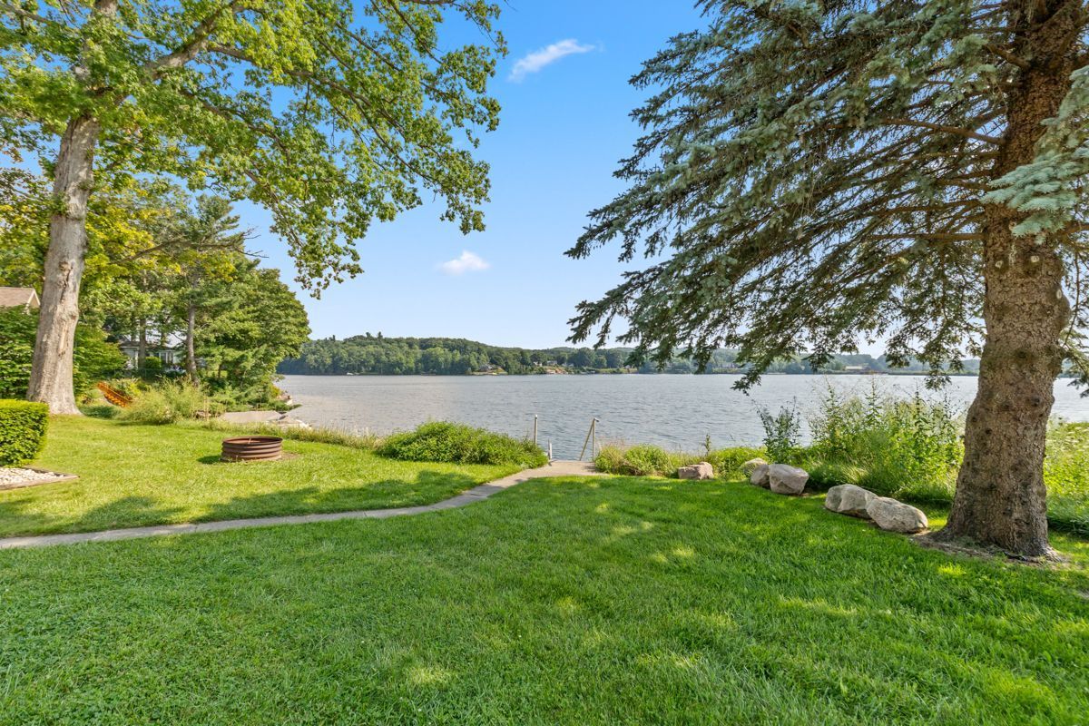 Lush green yard with a lake view, trees frame the scene at the Alpine Resort. Sunny day.