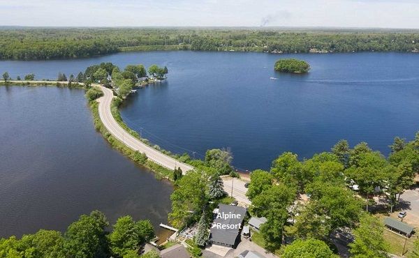 Aerial view of a road stretching across Croton Pond. Houses and trees line the shore.