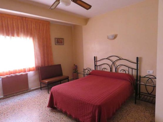 Un dormitorio con una cama y un ventilador de techo.