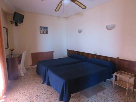 Una habitación de hotel con dos camas y un ventilador de techo.