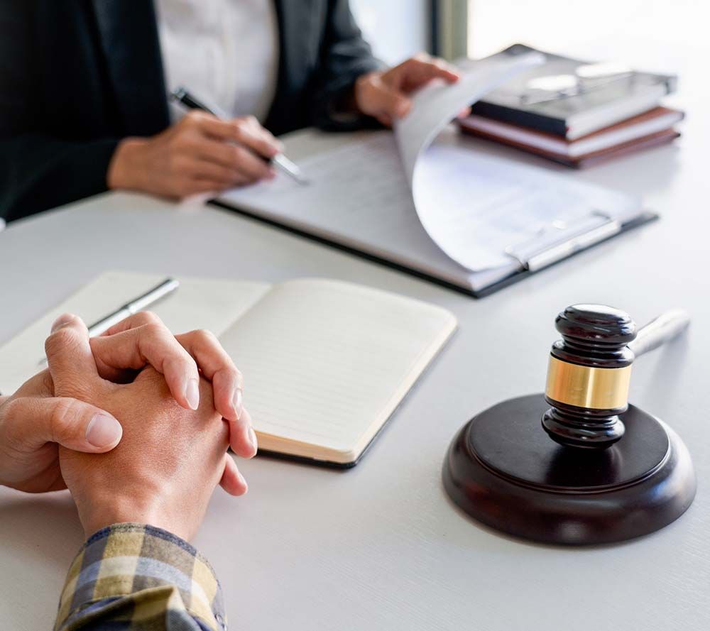 Apretón de manos en una reunión legal, con un mazo y documentos sobre el escritorio.