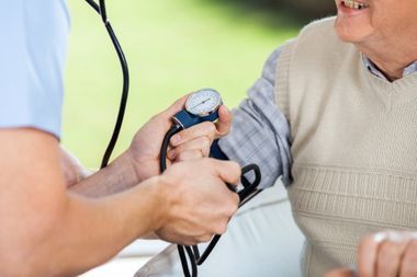 Pfleger misst den Blutdruck einer älteren Person