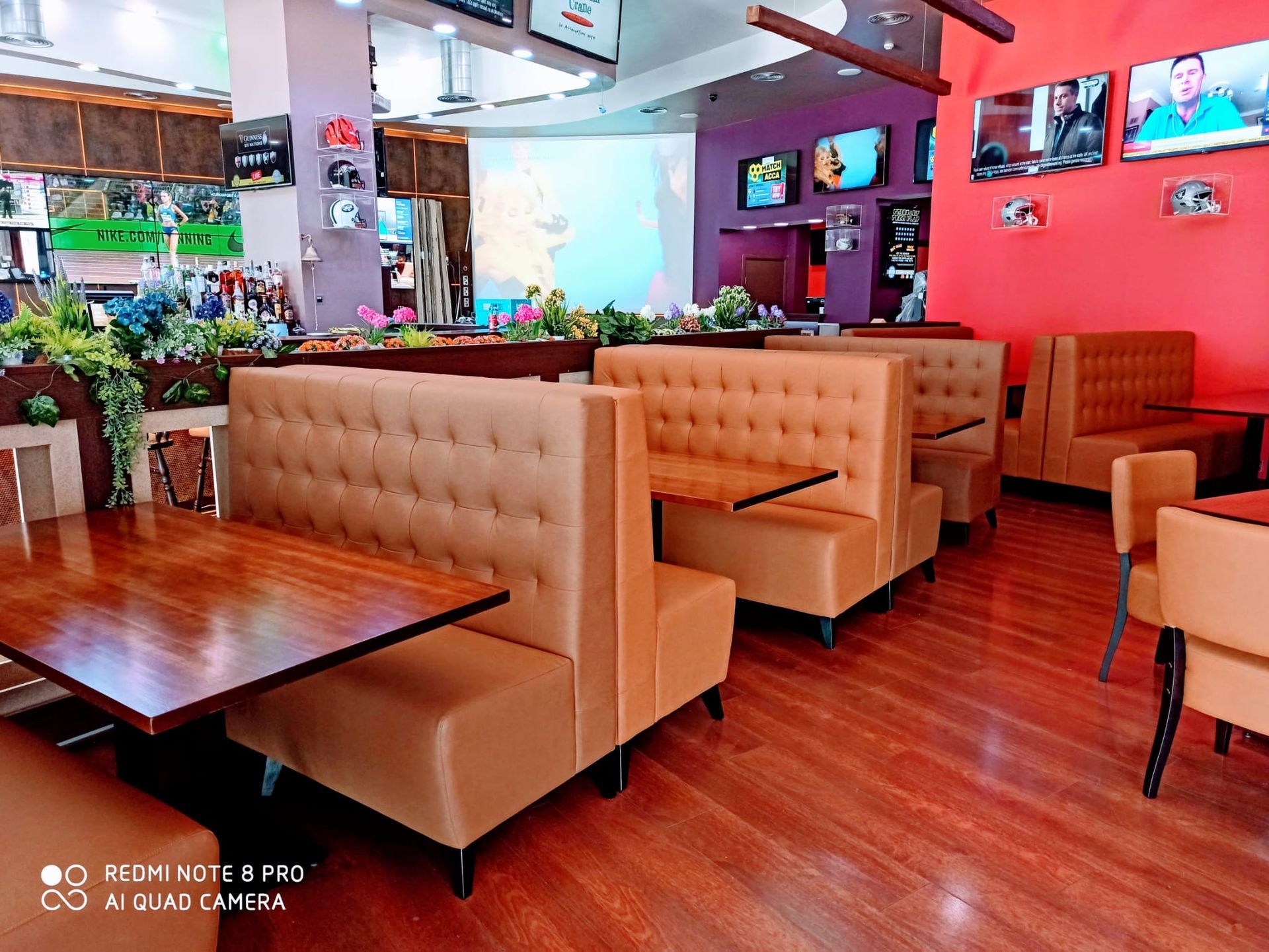Interior del restaurante con cabinas color beige, mesas de madera, paredes rojas y suelos de madera pulida.