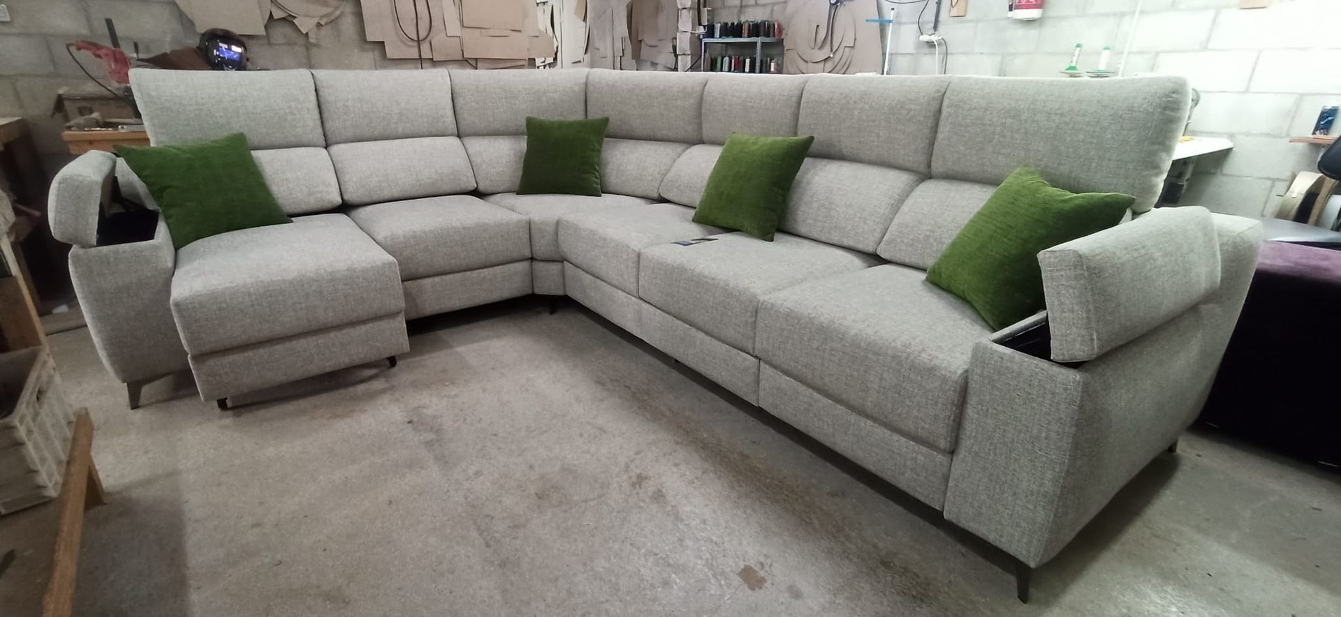 Sofá seccional gris claro con cojines decorativos verdes en una sala de estar.