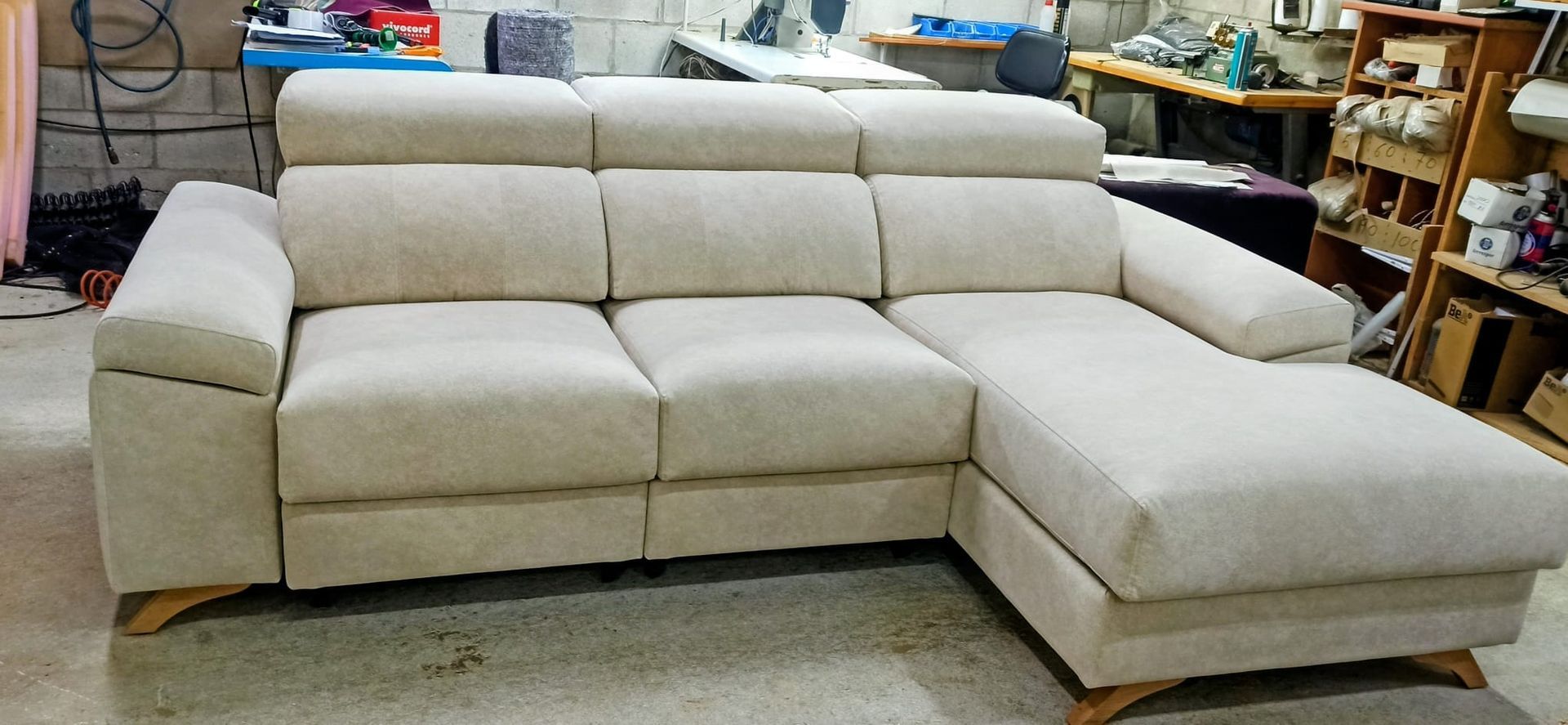 Sofá seccional beige con chaise longue en un taller o sala de exposición de muebles.