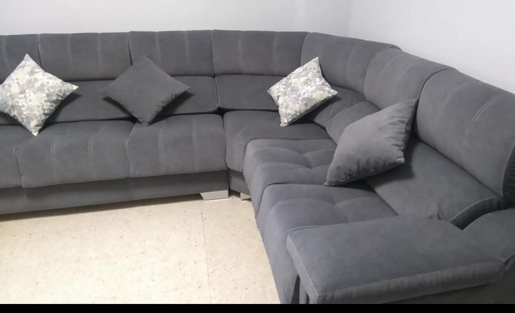 Sofá seccional gris con cojines estampados y lisos en una sala de estar.