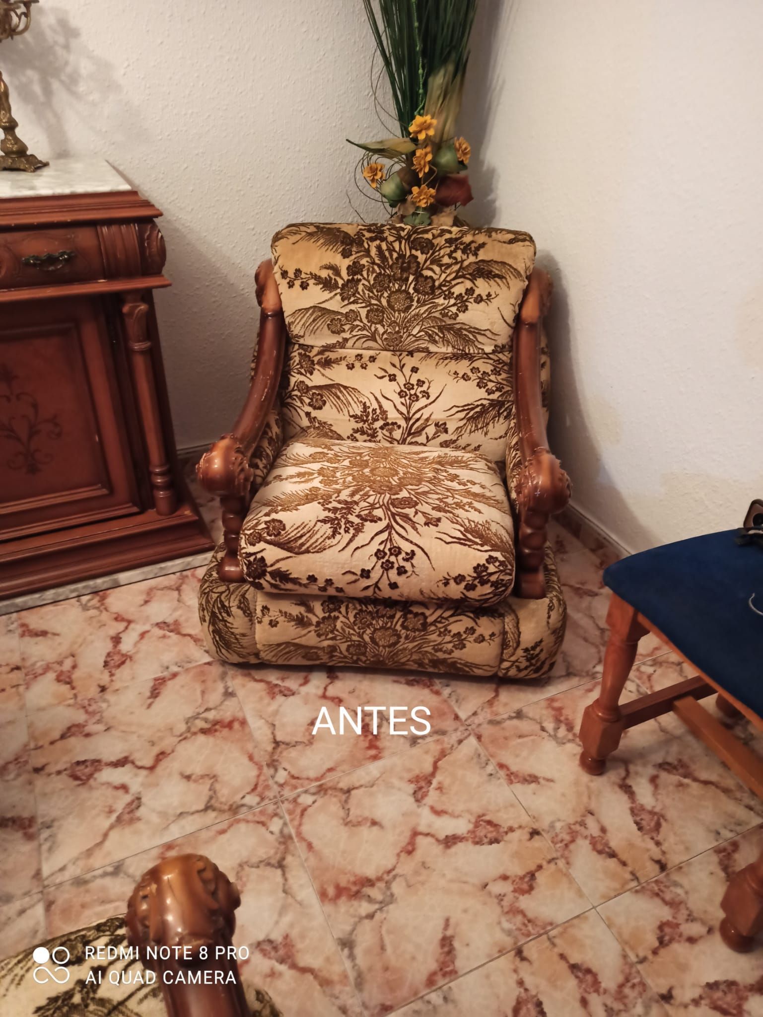 Sillón floral con tapicería beige y marrón en una sala de estar con suelo de mármol.