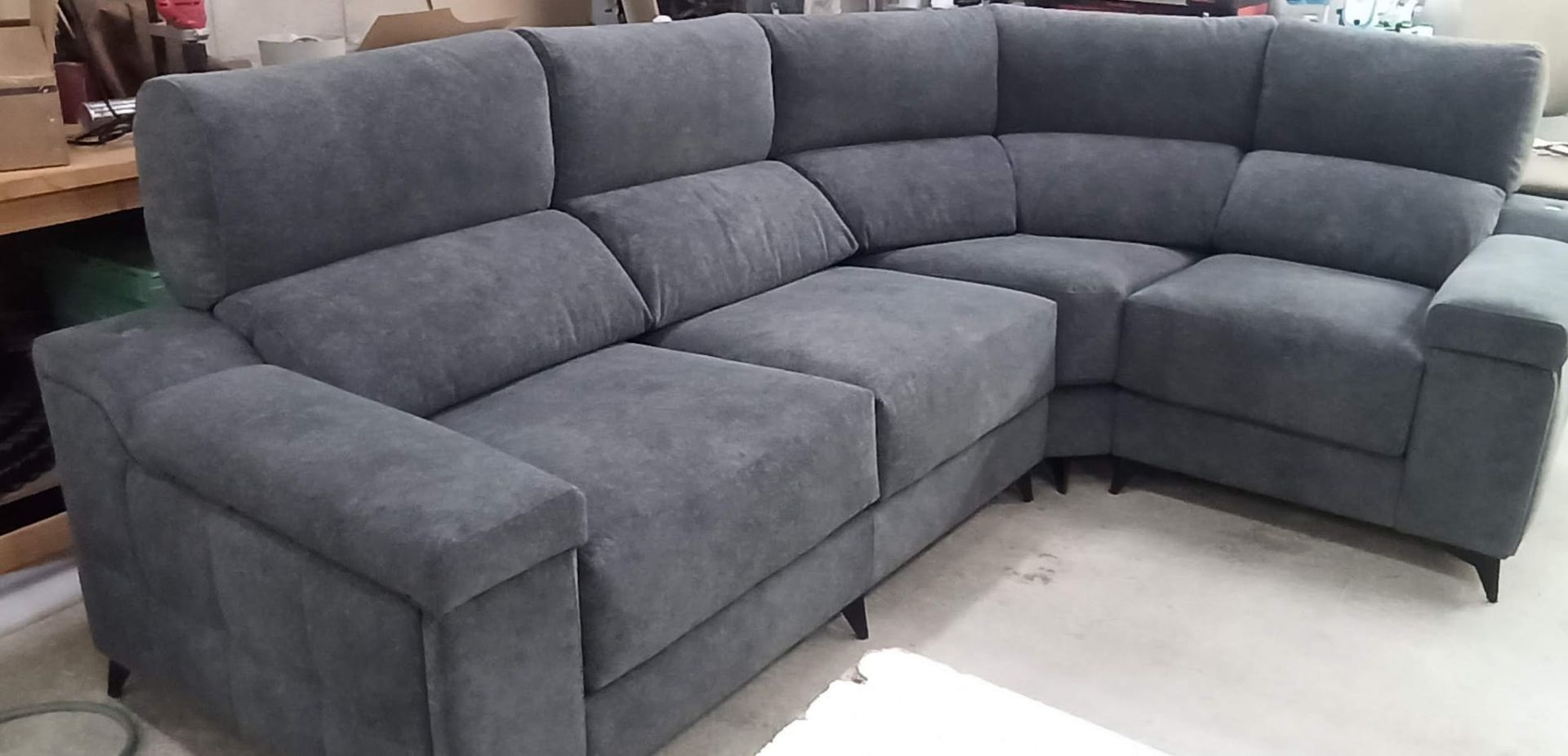 Sofá seccional gris con chaise longue en una sala de exposición.