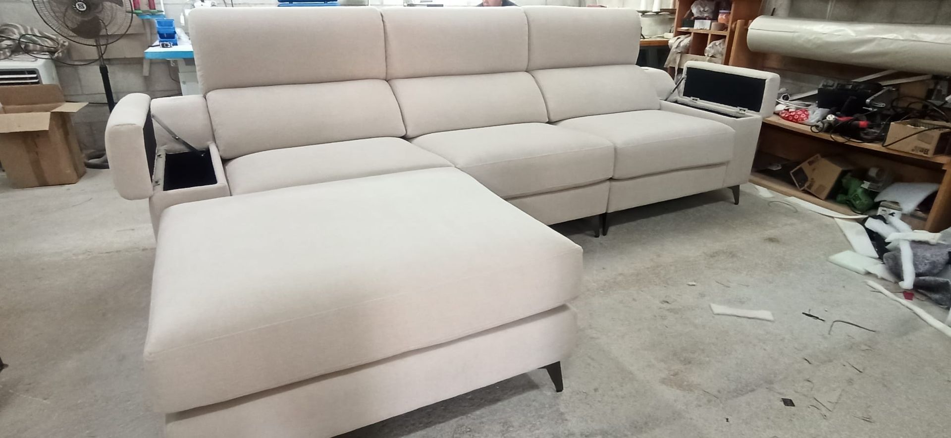 Sofá modular beige con chaise longue en una sala de estar o en una exposición de muebles.