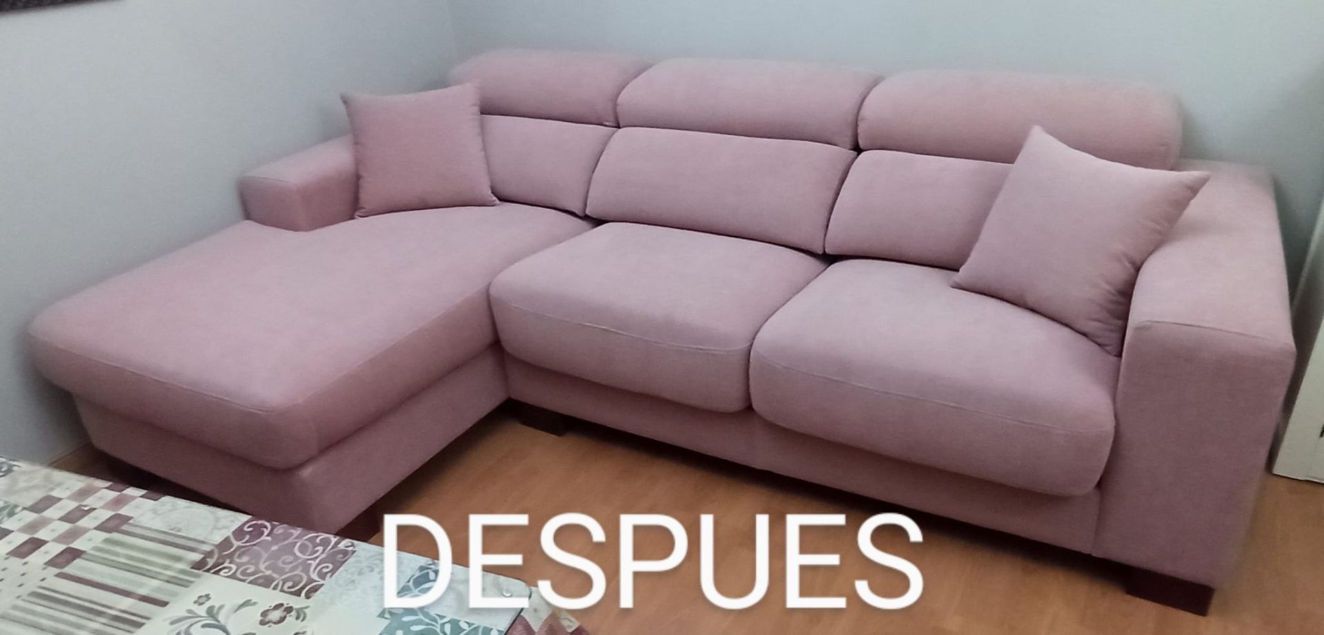Sofá seccional rosa en forma de L en una esquina, con la palabra 