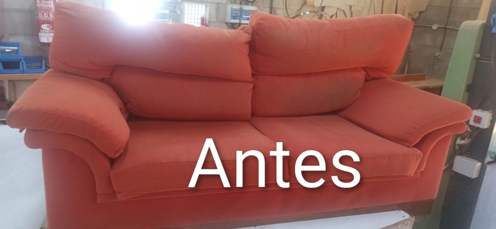 Sofá rojo en un taller o sala de exposición con el texto 
