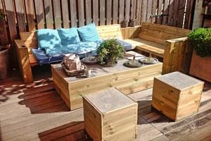 Un patio de madera con sofá, mesa y taburetes.