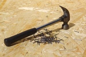 Un martillo y clavos están sobre una superficie de madera.