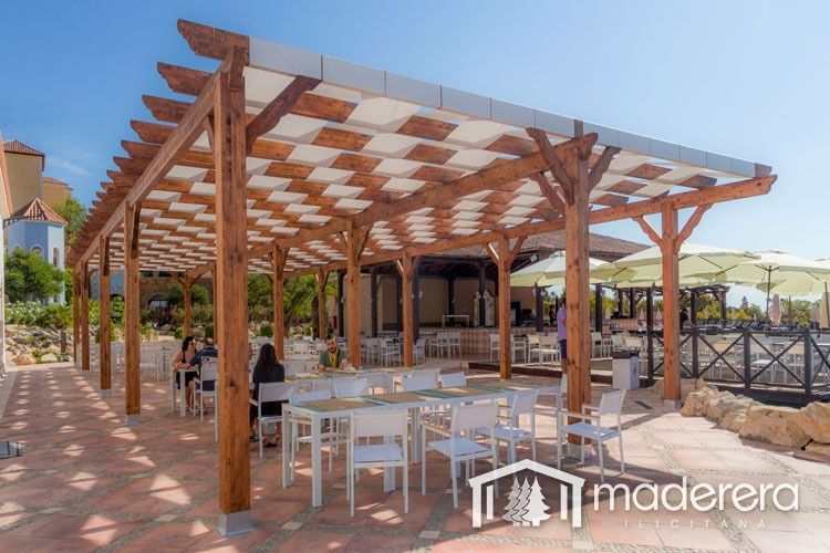 Un restaurante con mesas y sillas bajo una pérgola de madera.