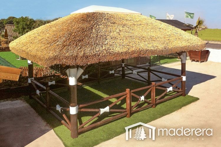 Un cenador con techo de paja y una valla de madera a su alrededor.