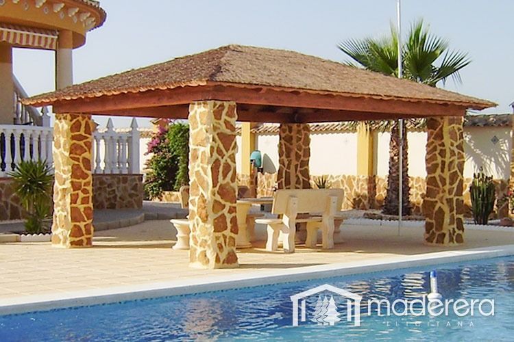 Un cenador de madera se encuentra junto a una piscina.