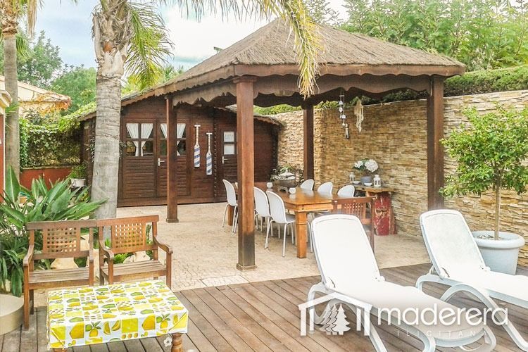 Un cenador de madera con techo de paja se encuentra encima de una plataforma de madera.