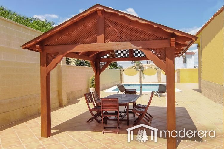 Un cenador de madera con una mesa y sillas debajo.