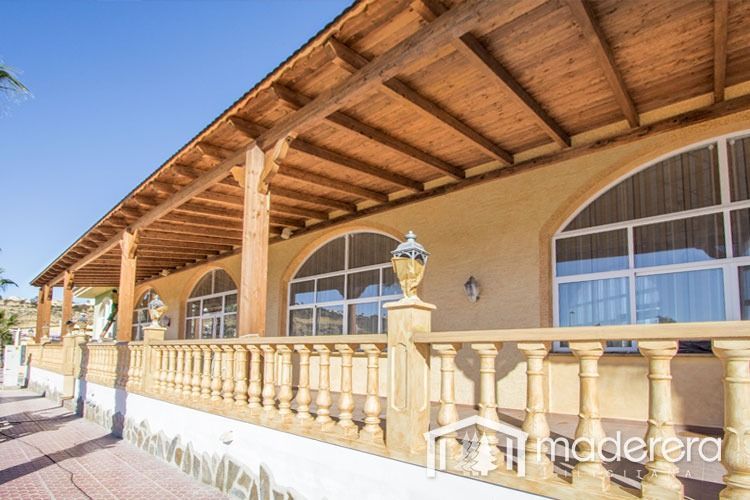Una casa grande con techo de madera y barandilla de madera