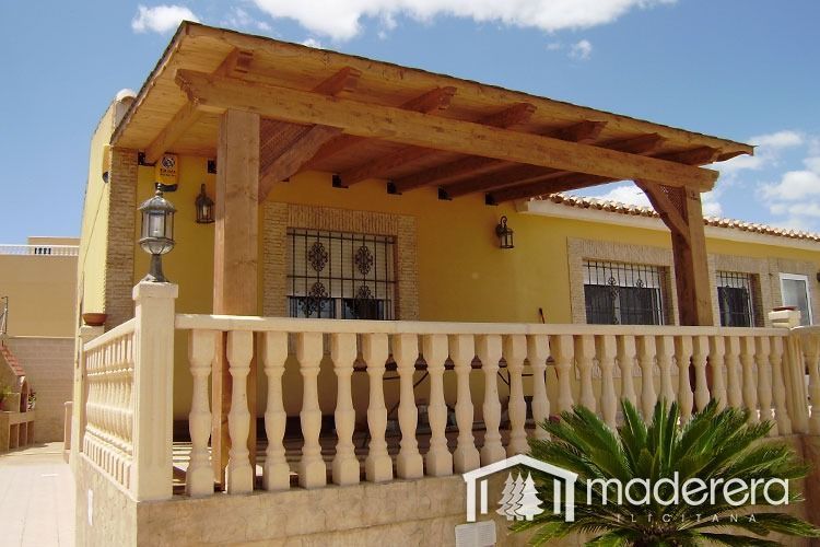 Una casa amarilla con un porche de madera y un cartel que dice maderarera