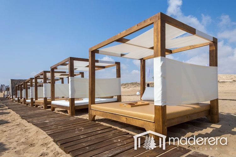 Una hilera de camas con dosel de madera en una playa.