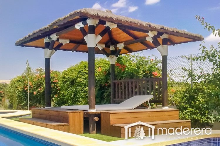 Un cenador de madera con techo de paja se encuentra junto a una piscina.