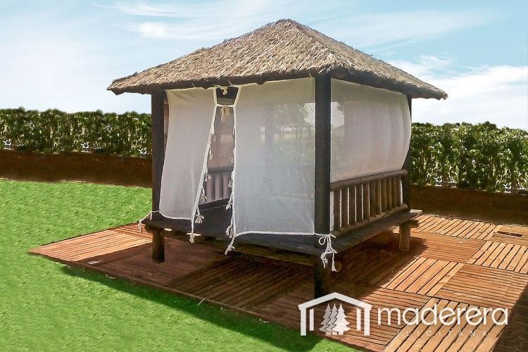 Un cenador de madera con techo de paja y cortinas blancas.