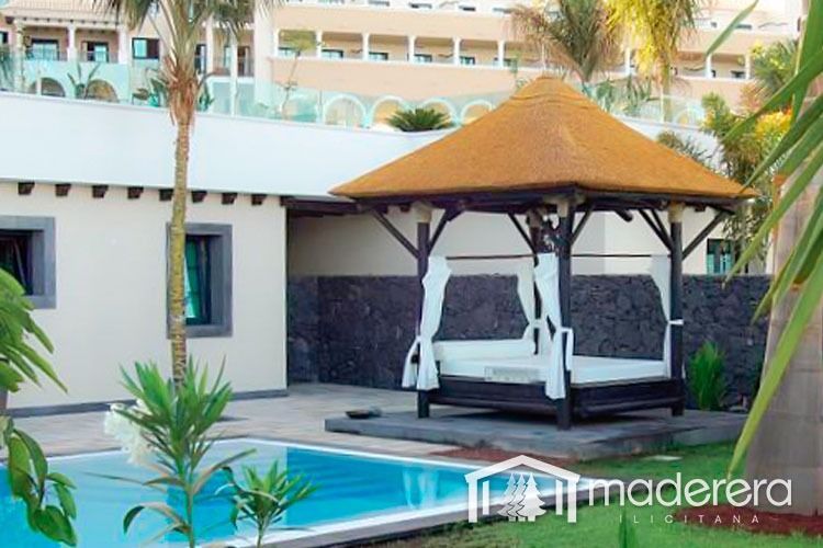 Un cenador con techo de paja se encuentra junto a una piscina.