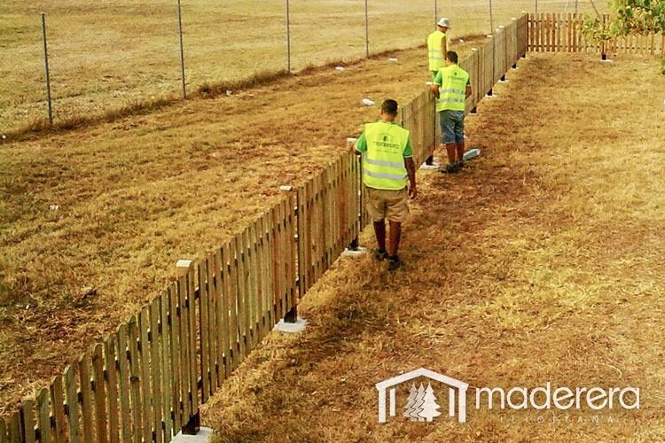 Un grupo de hombres está de pie junto a una valla de madera.
