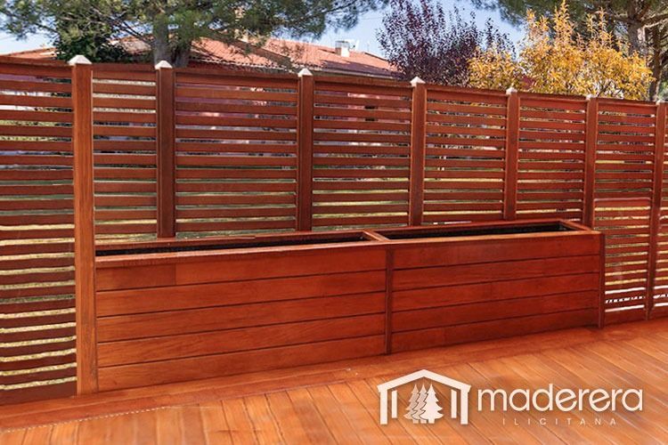 Una valla de madera con dos jardineras de madera delante de ella.