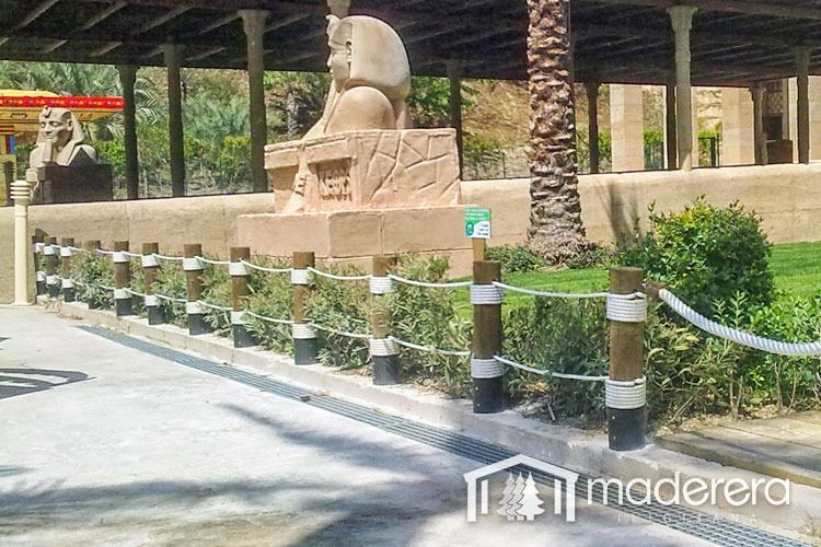 Una valla de madera con una estatua de una esfinge al fondo.