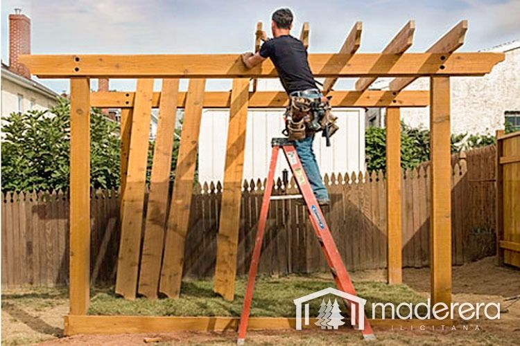 Un hombre está de pie en una escalera trabajando en una estructura de madera.