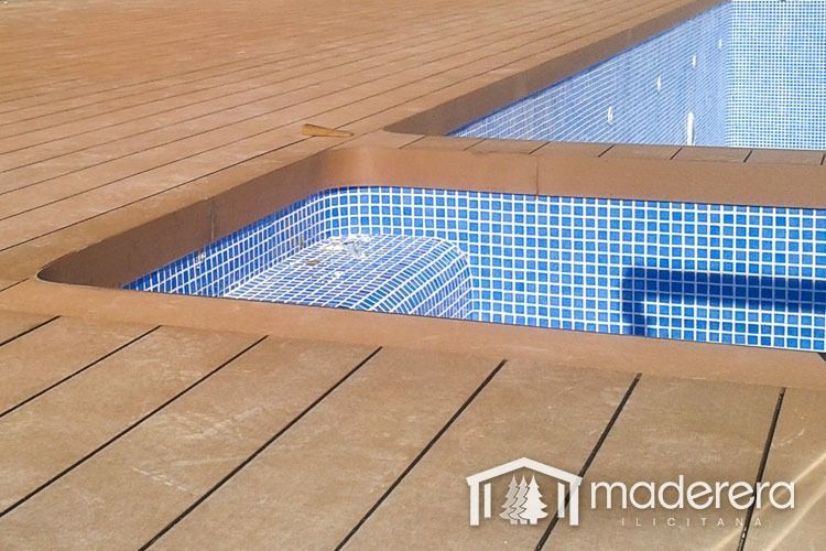 Una piscina con una plataforma de madera que la rodea.