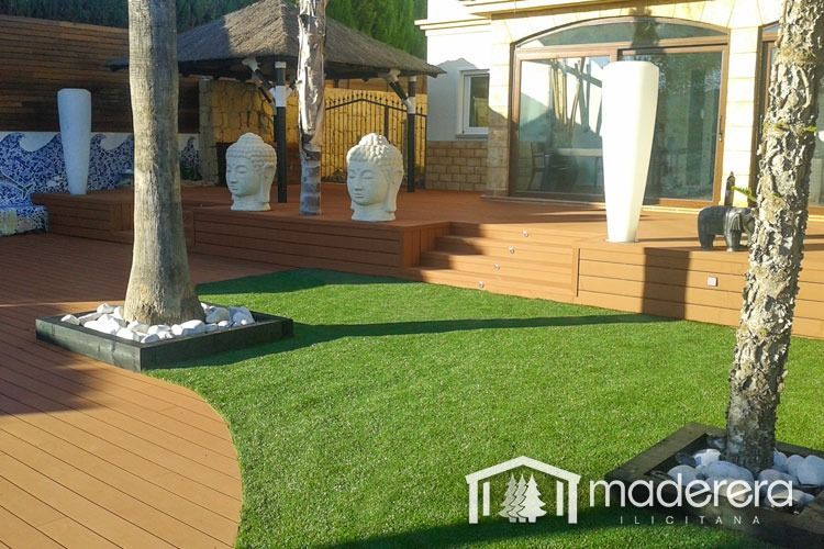 Una terraza de madera está rodeada por un exuberante césped verde.