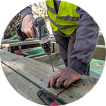 Un hombre está usando un taladro para hacer un agujero en un trozo de madera.