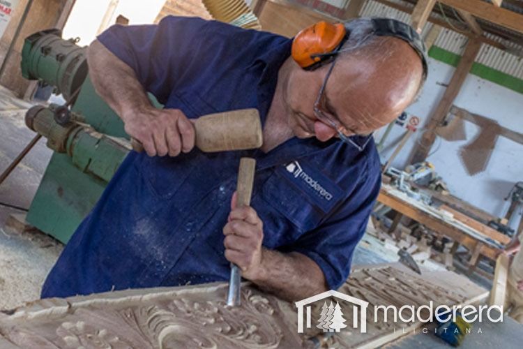 Un hombre con una camisa azul está tallando un trozo de madera.