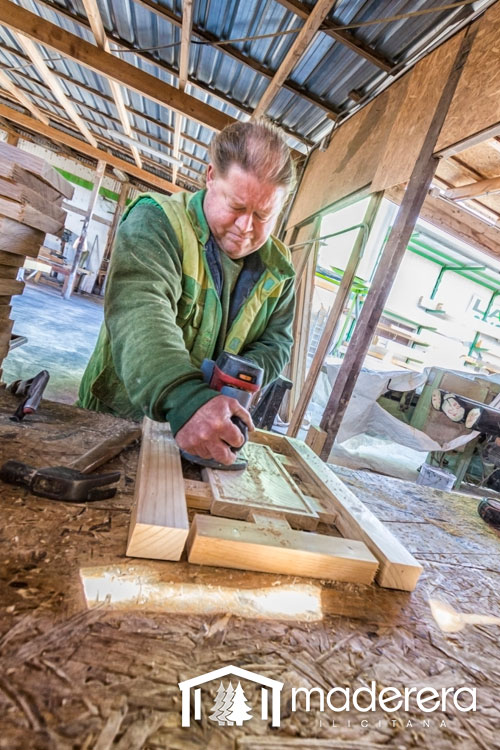 Un hombre está lijando un trozo de madera en un taller.