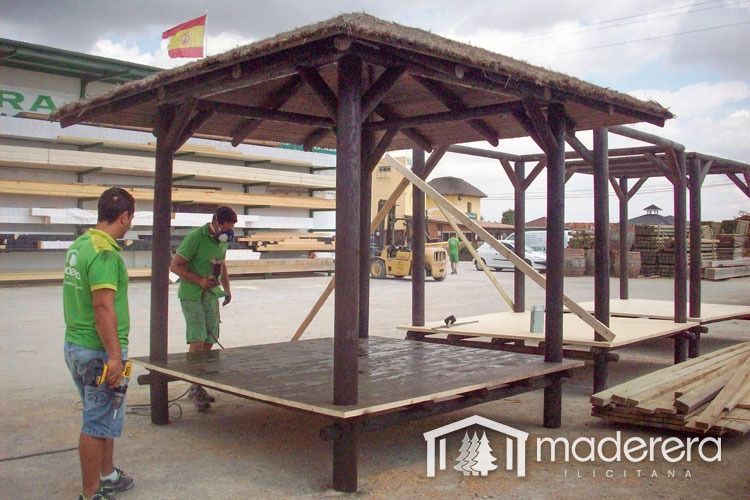 Dos hombres están trabajando en una estructura de madera con techo de paja.