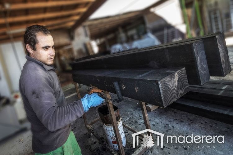 Un hombre está pintando un trozo de madera en un taller.