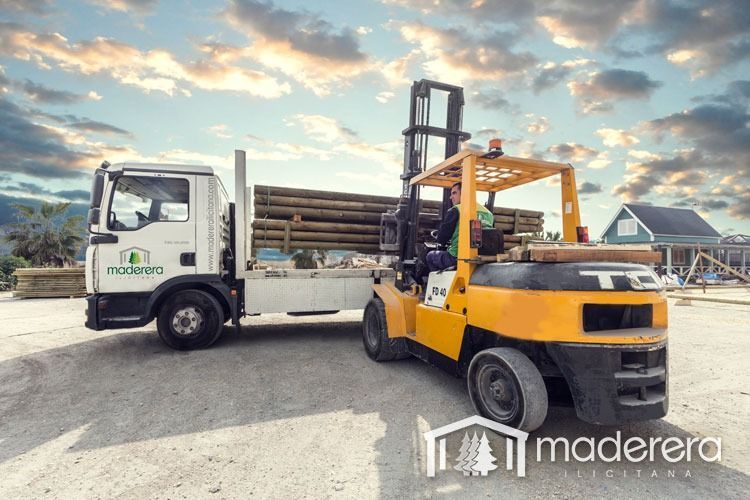 Una carretilla elevadora está tirando de un camión lleno de troncos.