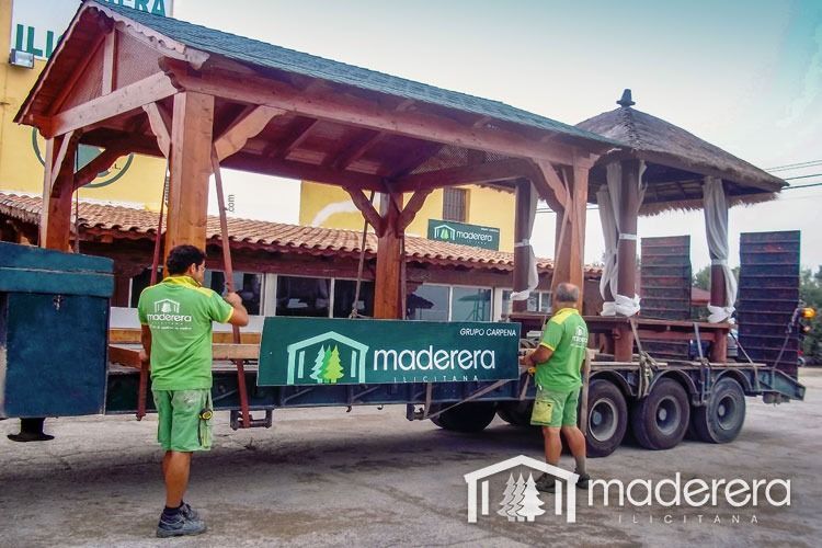 Dos hombres están parados junto a un remolque que dice madera.
