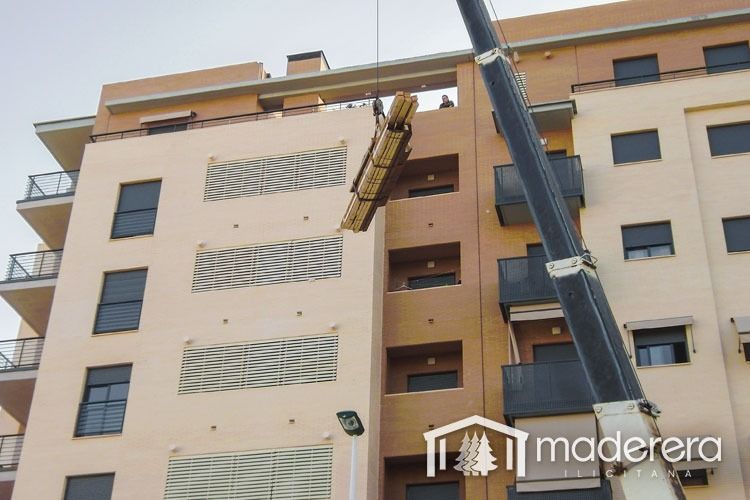 Una grúa está levantando un trozo de madera en la parte superior de un edificio.