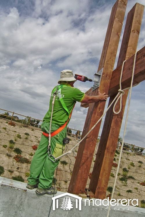 Un hombre está trabajando en una cruz de madera con un taladro.