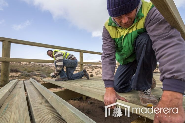 Dos hombres están trabajando en una plataforma de madera.